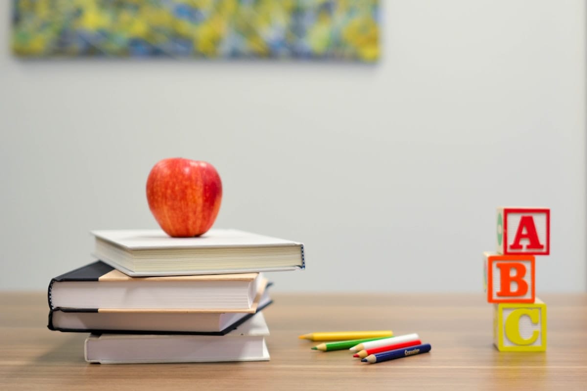 Bureau d'école avec une pomme posée sur des livres et des cubes ABC
