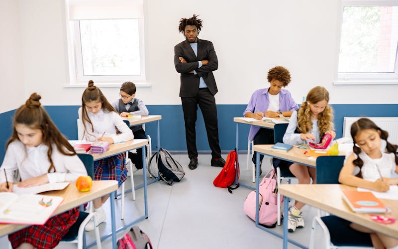 Enseignant entouré d'élèves concentrés dans une salle de classe lumineuse